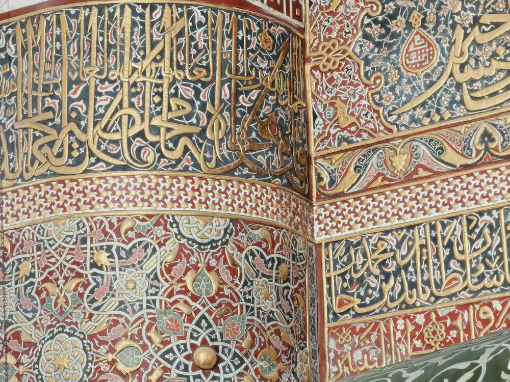 Detail kaligrafi dan motif geometris berwarna emas